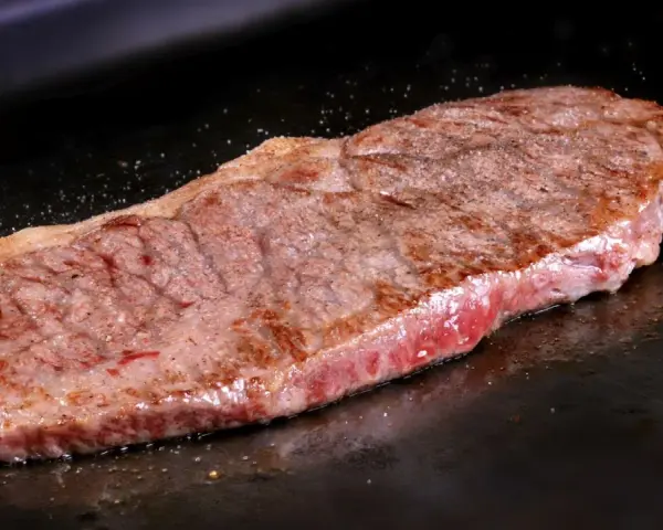 Filete de ternera jugoso cocinándose en una plancha. Perfecto para tus recetas con filetes de ternera.