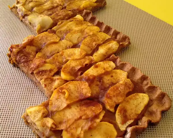 Dos porciones de tarta de manzana casera, con trozos de manzana dorados y espolvoreados con canela, sobre una base de masa crujiente.
