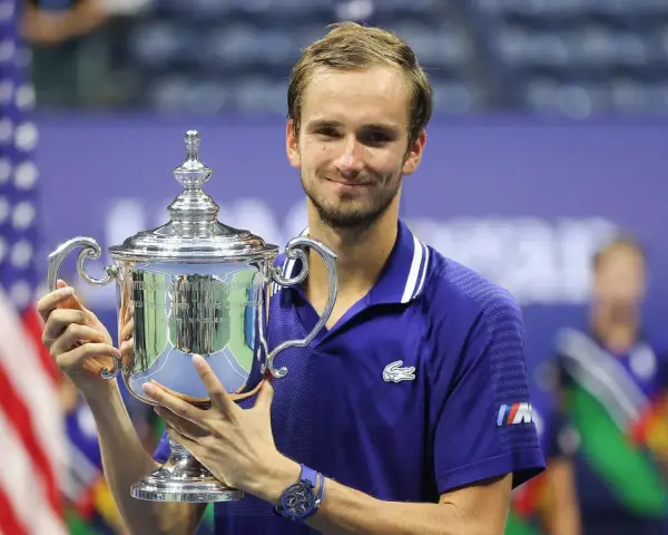 Daniil Medvedev, sonriendo, sostiene el trofeo del US Open, un logro que lo consolida entre los grandes de los medvedev grand slams.
