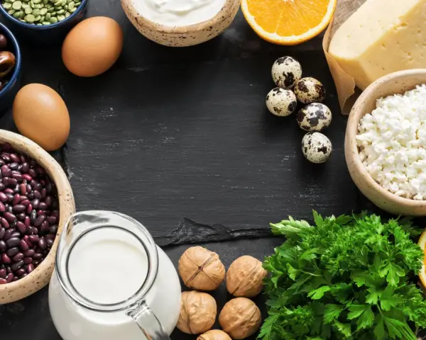 Vielfalt an Lebensmitteln mit Calcium: Milch, Käse, Quark, Eier, Bohnen, Datteln, Nüsse, Orangen und Petersilie.