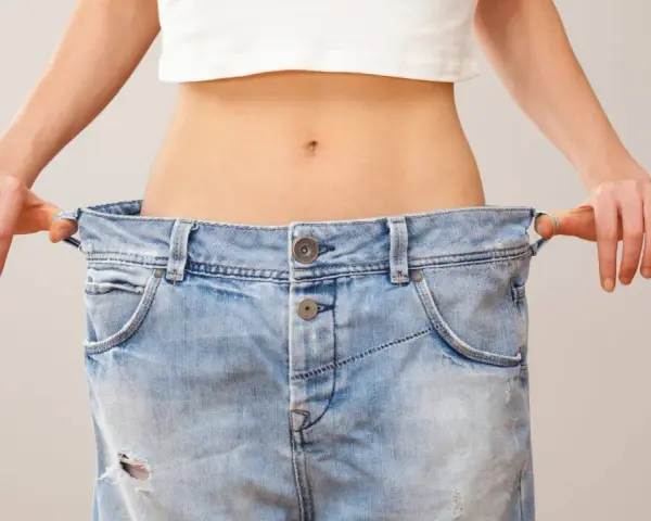 En person visar hur snabbt man kan gå ner i vikt genom att hålla upp ett par alldeles för stora jeans.
