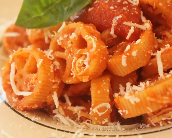 Pasta con ruote e rigatoni conditi con una ricca salsa di pomodoro Bimby, spolverata di parmigiano e guarnita con una foglia di basilico.