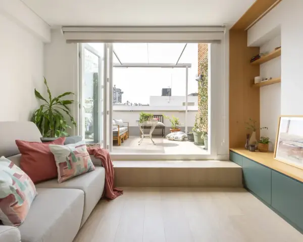 Ideas para decorar un salón rectangular: sofá gris, cojines coloridos, plantas y acceso a terraza.