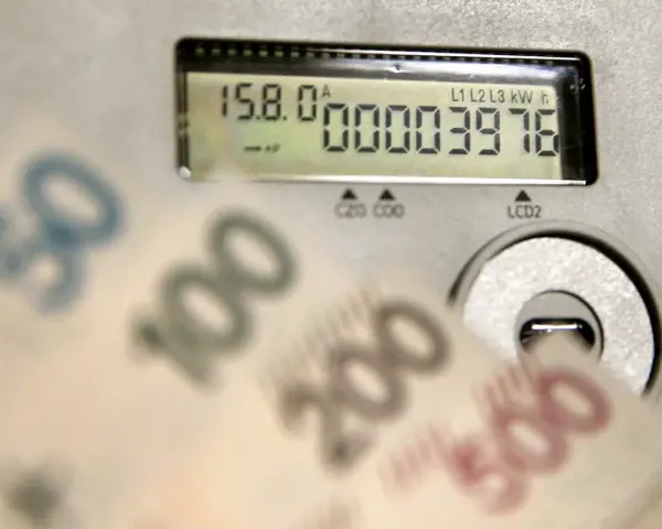 Opłata kogeneracyjna co to? Licznik energii i banknoty 50, 100, 200, 500 zł sugerują wysokie rachunki za prąd.