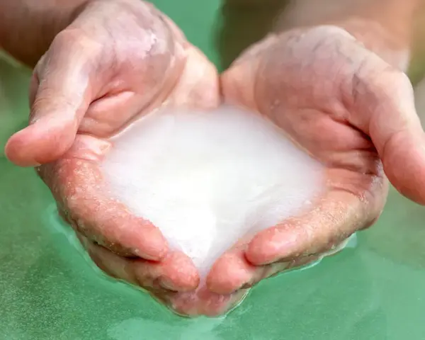 Hands cupped, holding foamy water, ready for a relaxing magnesium foot soak.