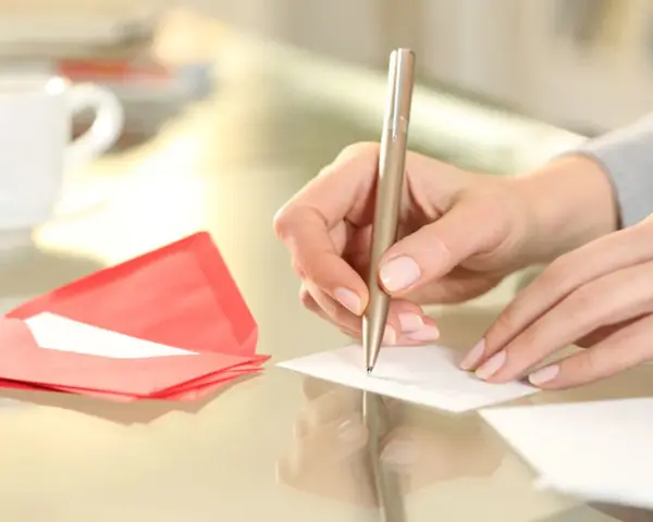 Main tenant rédige un modèle d'autorisation parentale TAM. Une tasse de café et une enveloppe rouge sont à proximité.