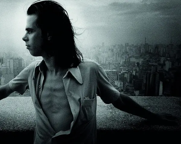 Młody Nick Cave, z rozwianymi włosami, spogląda na miasto. Jego muzyka, jak ten widok, pełna jest mroku i piękna.