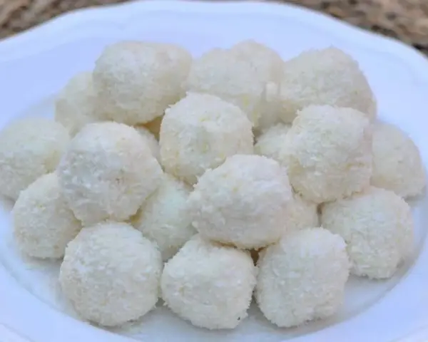 Un mucchio di dolci palline di cocco su un piatto bianco, perfette per una pausa golosa.