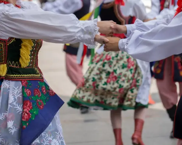 Tancerze w barwnych strojach ludowych, żywa muzyka folkowa w tle.