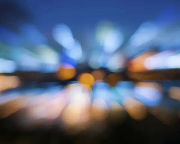 Effetto **vedere sfocato con occhiali nuovi**, luci urbane che si espandono in un caleidoscopio di colori blu e arancio.