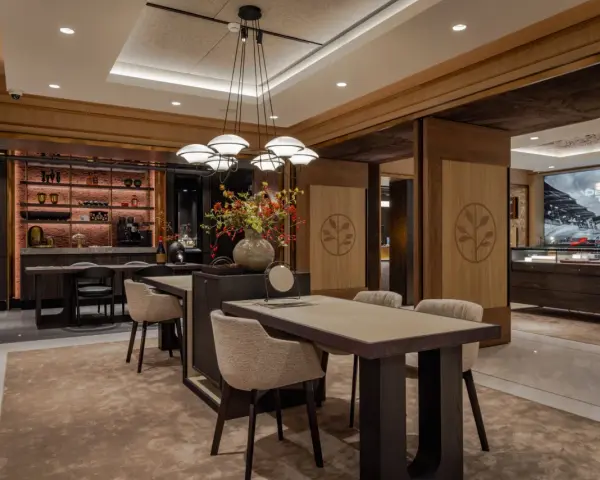 Interno di un elegante **progetto gioielleria** con tavoli in legno, sedie imbottite, un'area bar e vetrine espositive.
