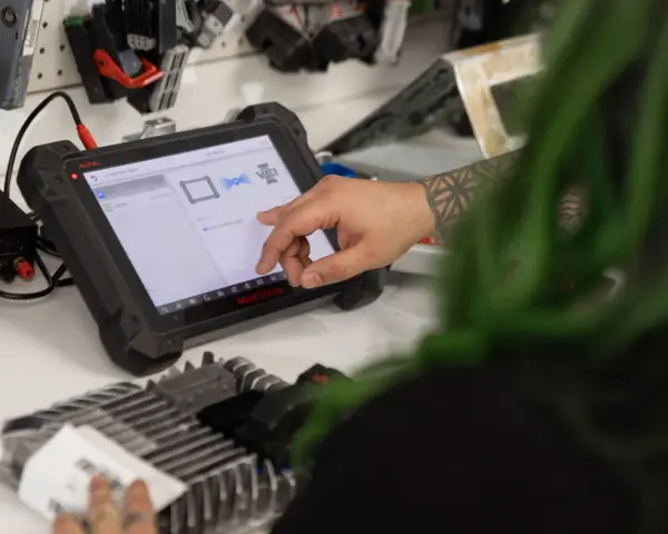 Mechanic uses a diagnostic tablet to connect to a car's ecm.