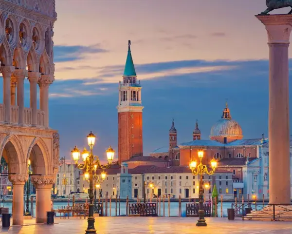 Piazza San Marco a Venezia al tramonto, con il Palazzo Ducale, il Campanile e la Basilica di San Giorgio Maggiore illuminati.