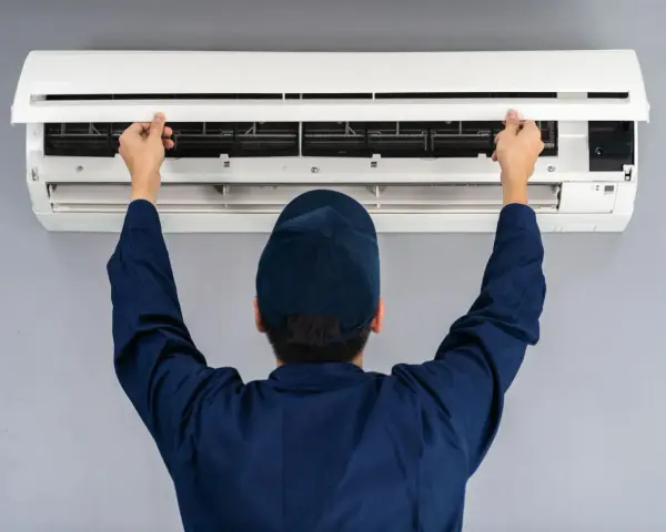 Tecnico controlla un condizionatore che non raffredda, aprendo il pannello frontale per ispezionare i filtri.