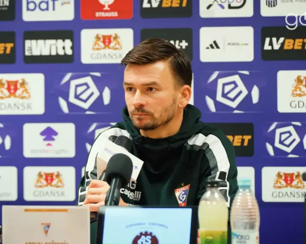 Trener rozmawia o lechia transfery. Na ścianie logo Lechii Gdańsk.
