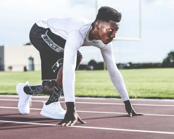 En sprinter i startblocken, redo för en explosiv anaerob sprint. Träningen balanserar aerob och anaerob kondition.