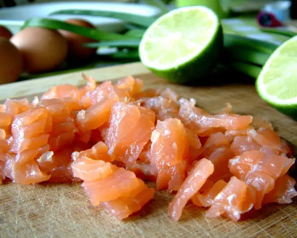 Pokrojony łosoś, jajka i limonka na desce. Idealne składniki na pyszny omlet z łososiem.