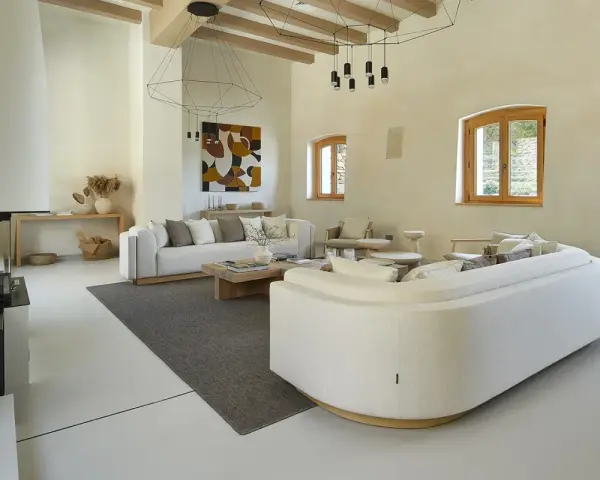 Salón moderno con sofás blancos, chimenea y suelo de microcemento sobre azulejos.