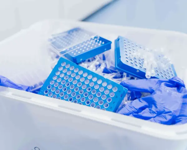 Niebieskie płytki do pipetowania i rękawiczki w pojemniku na odpady laboratoryjne. Kod odpadu 16 03 04.