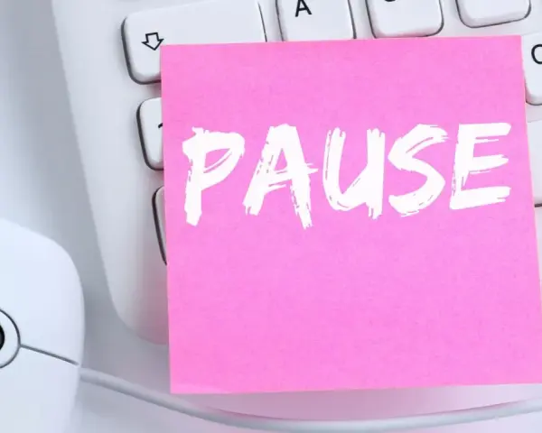 Ein rosa Zettel mit dem Wort "PAUSE" liegt auf einer Tastatur neben einer Maus. Ein Hinweis auf das **bildschirmpause gesetz**.