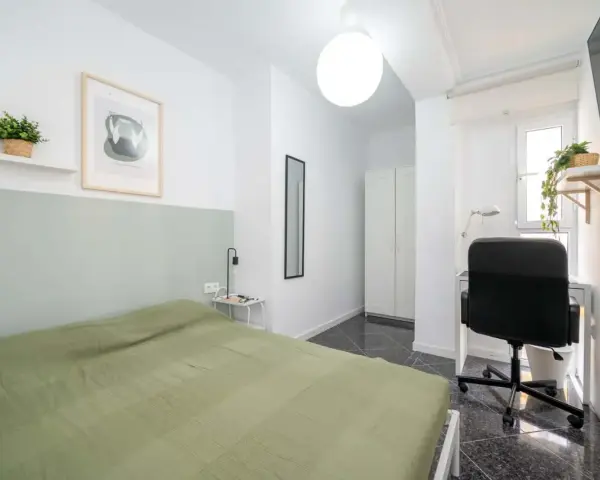 Habitación luminosa con cama, escritorio y armario. Ideal como piso para estudiantes, con decoración moderna y plantas.