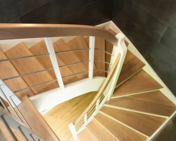Drewniane schody kacze z białymi balustradami i metalowymi poręczami, prowadzące w dół.