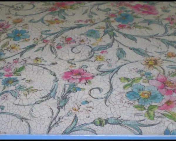 Un patrón de flores y hojas en tonos pastel sobre una superficie con craquelado pintura, evocando un estilo vintage.