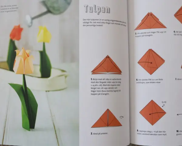 Vackra vika pappersblommor i form av tulpaner, en klassiker inom origamikonsten. En orange tulpan i förgrunden, med en röd och en gul i bakgrunden.