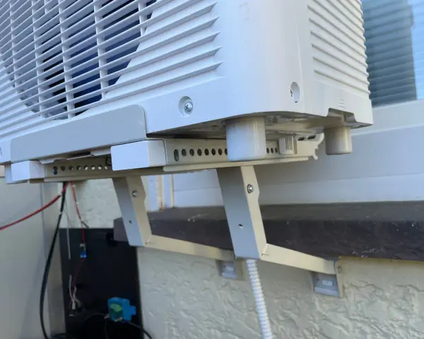 Klimaanlage mit Halterung und Kabeln. Der Kondenswasser Abfluss ist hier nicht sichtbar, aber die Einheit ist für die Ableitung vorbereitet.