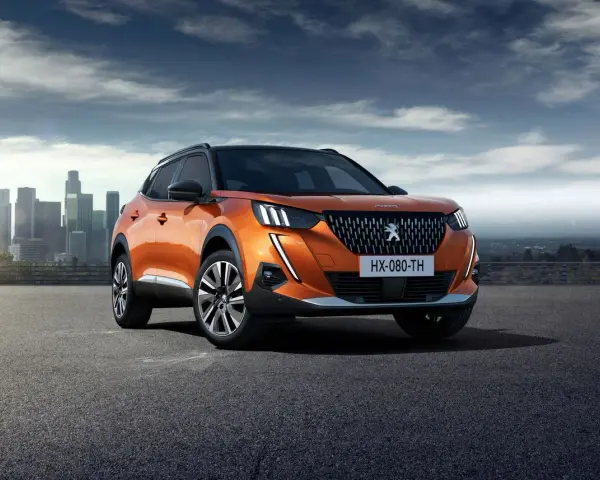 Pomarańczowy Peugeot 2008 na tle miasta. Sprawdź jego wymiary i możliwości.