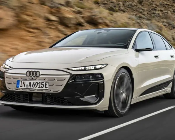 Jasnoszary Audi A6 e-tron z czarnymi akcentami jedzie po drodze.