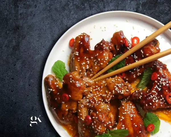 Pyszne skrzydełka teriyaki, błyszczące od sosu, posypane sezamem i ozdobione plasterkami chili.