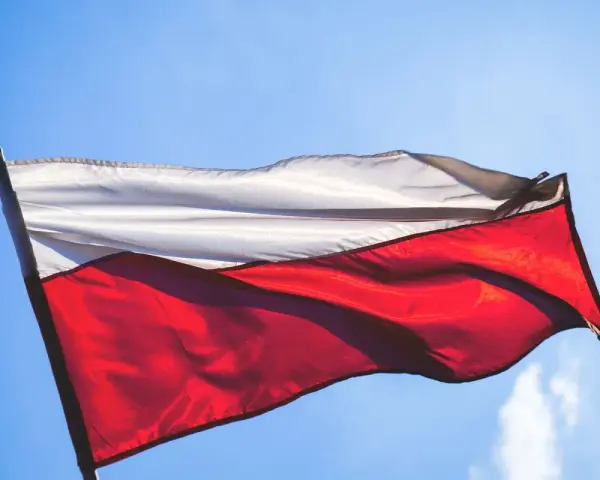 Flaga Polski, biało-czerwona, powiewa na tle błękitnego nieba.