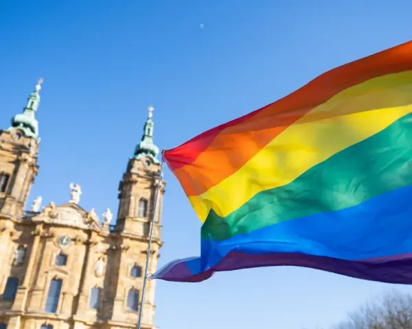 Regenbogenfahne weht vor evangelischer Kirche. Ein Zeichen für Akzeptanz und Vielfalt, das die Botschaft der evangelischen Kirche LGBT widerspiegelt.