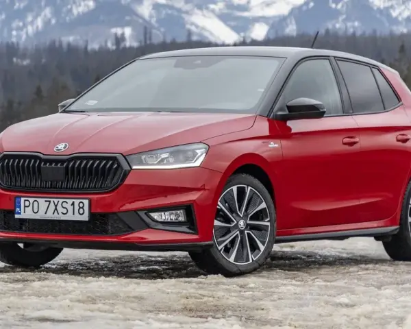 Czerwona Skoda Fabia Monte Carlo z czarnym dachem na tle ośnieżonych gór.