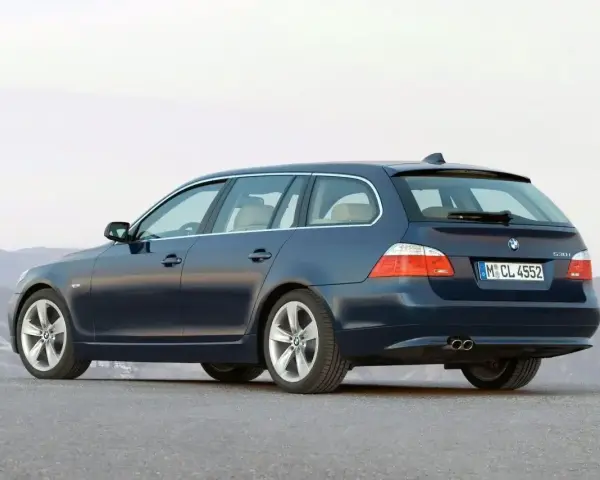 Granatowe BMW E61, kombi, stoi na pustej drodze.