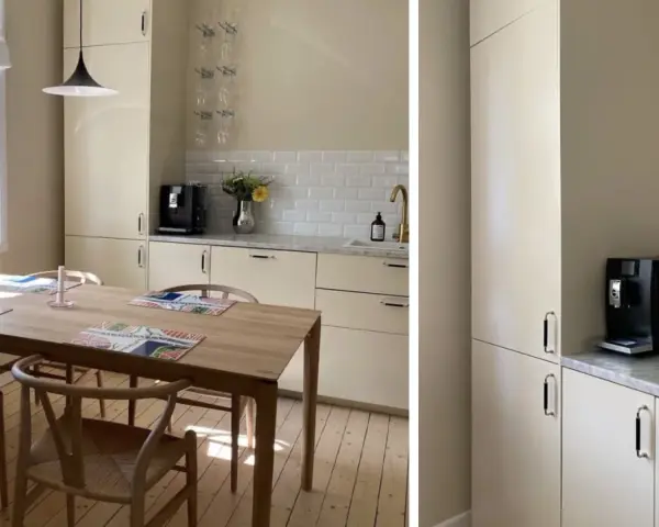 Ljust kök med träbord och stolar. Nya köksluckor ger ett fräscht intryck. Kaffemaskin och blommor på bänken.