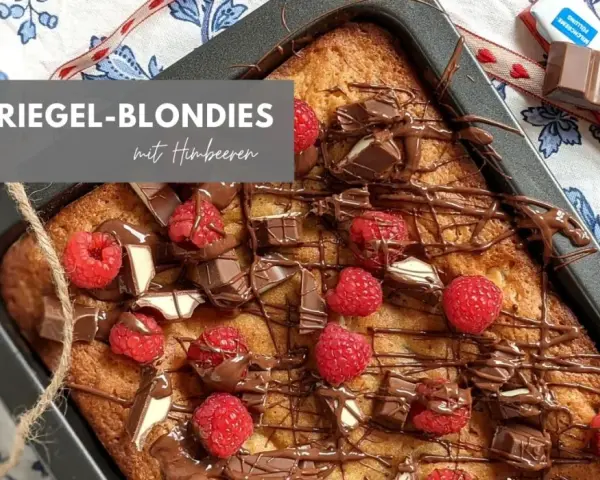 Kinderriegel-Blondies mit Himbeeren: Ein saftiger Kuchen, dekoriert mit Schokolade und frischen Beeren. Perfekt für das Blondies Rezept!