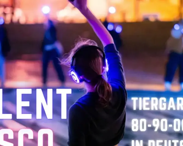 Silent Disco Berlin im Tiergarten. Leute tanzen mit leuchtenden Kopfhörern im Dunkeln.