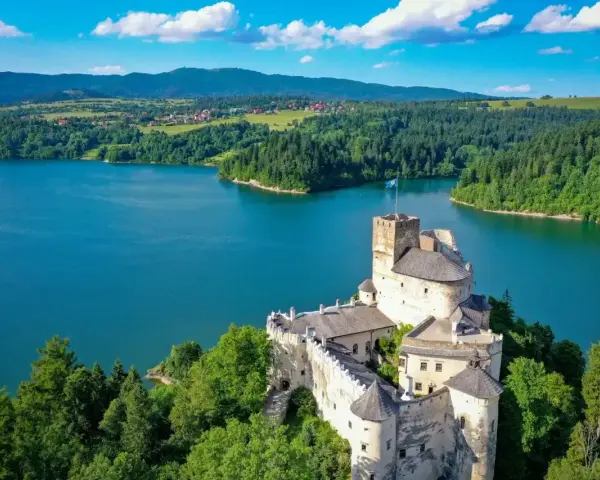 Zamek w Niedzicy góruje nad turkusowym zalewem czorsztyńskim, otoczony zielonymi lasami i górami.