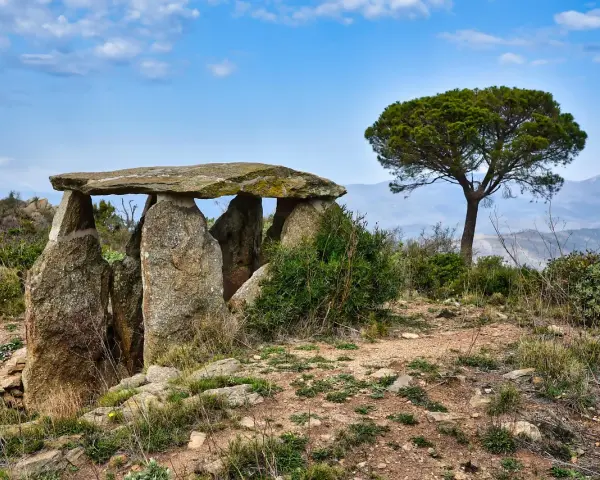 Starożytny menhir, kamienna konstrukcja, stoi na wzgórzu pod błękitnym niebem.
