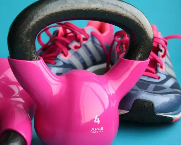 Różowe kettlebelle i buty sportowe marki Adidas gotowe do treningu.