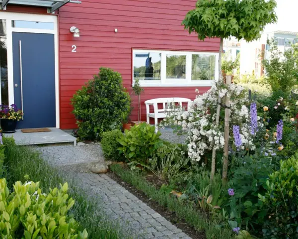 Reihenhaus mit kleinem Vorgarten: Ideen für blühende Beete, ein Weg aus Granit und eine weiße Bank laden zum Verweilen ein.