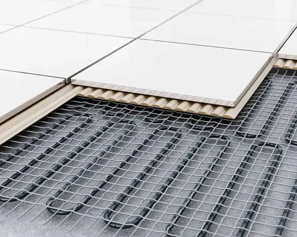 Warstwa izolacyjna i siatka z rurkami do układania ogrzewania podłogowego, przykryte płytkami.