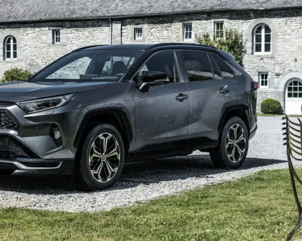 Szary Toyota RAV4 Hybrid przed kamiennym budynkiem. Zastanawiasz się, ile kosztuje Toyota RAV4 Hybrid?