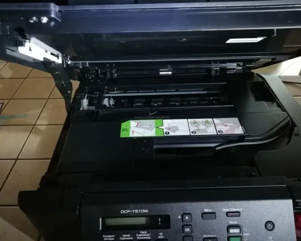 Otwarta drukarka Brother DCP-T510W z widocznymi instrukcjami i panelem sterowania.
