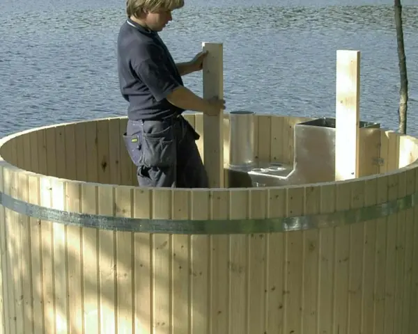 Man bygga badtunna vid sjön. Träet är nytt och redo för montering.