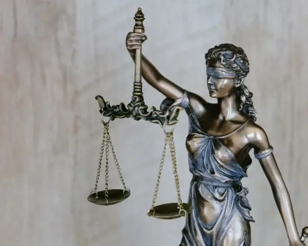 Figurka Temidy z wagą symbolizuje sprawiedliwość, która jest kluczowa przy nowelizacji kodeksu karnego.