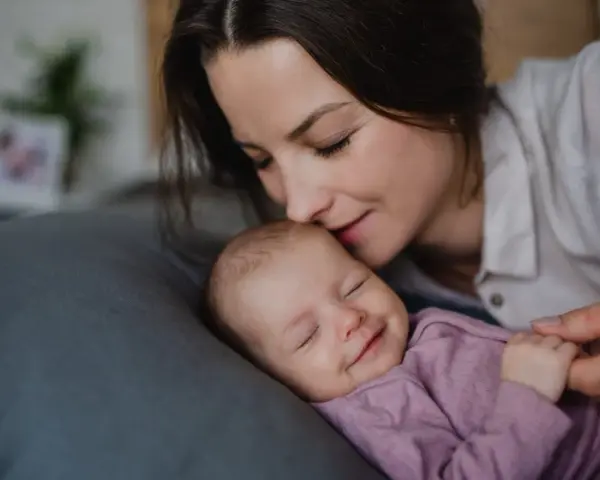 Mama całuje śpiące dziecko. Wkrótce wybierzemy dla niej słodkie imiona dla dziewczynki.