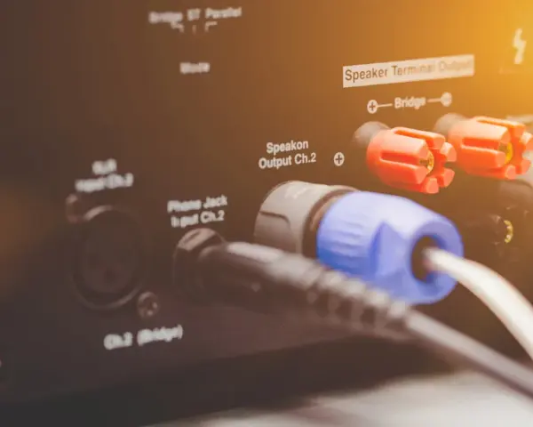 Złącza Speakon i zaciski głośnikowe na wzmacniaczu, pokazujące różne **cable types** do podłączenia sprzętu audio.